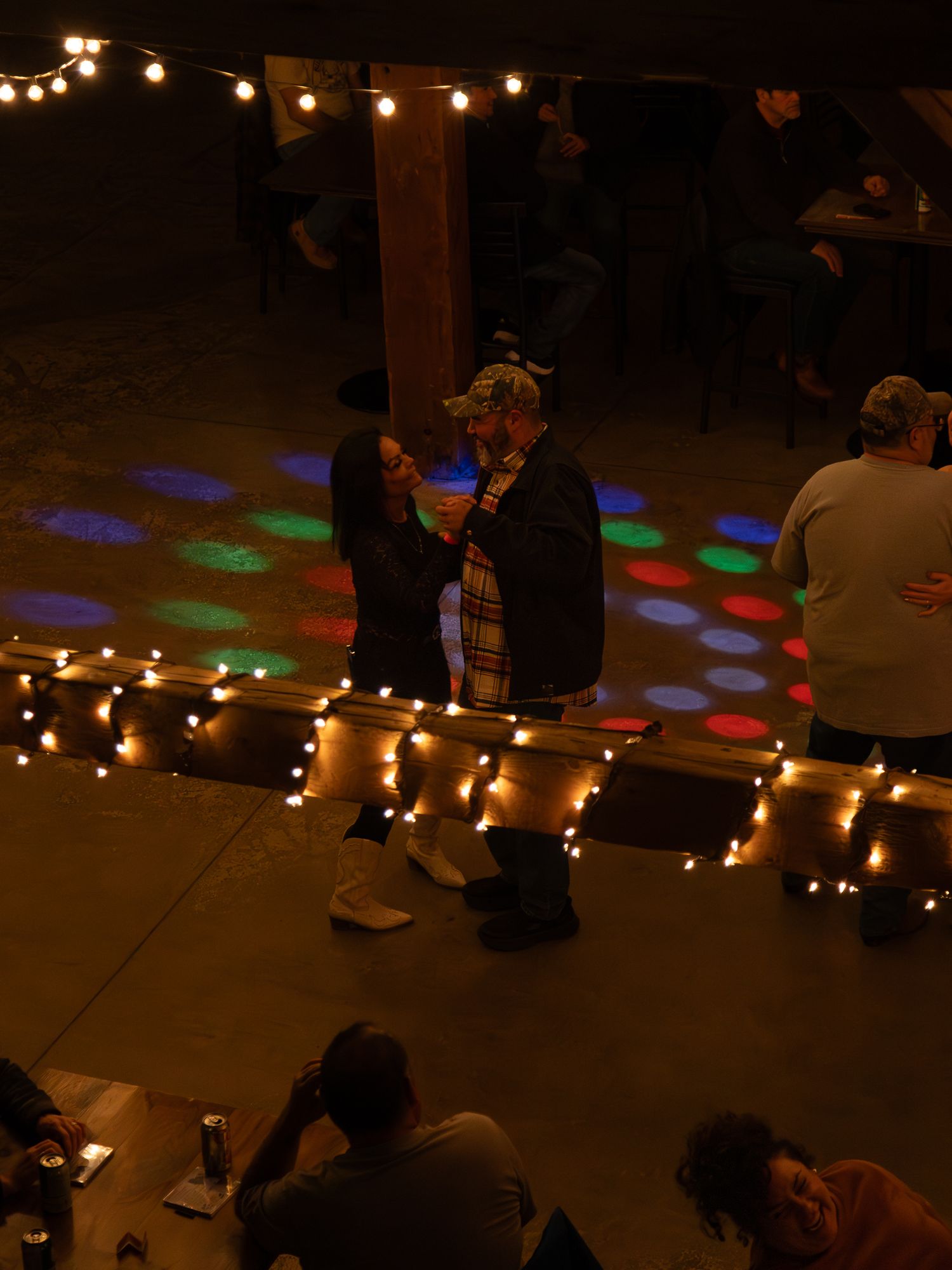 Colorful disco lights illuminate a dark floor space with string lights creating patterns along the ground.