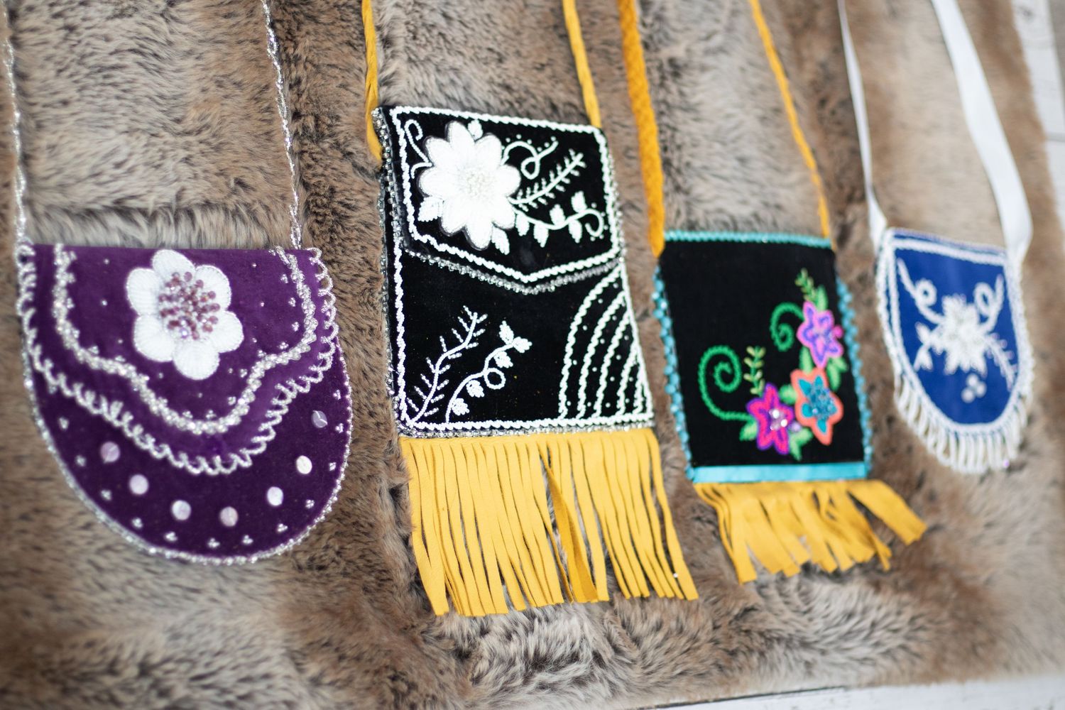 Collection of handmade beaded accessories with floral designs and yellow fringe displayed on textured surface.