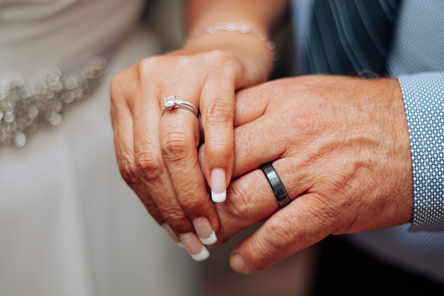 Close-up of hands showing wedding rings and jewelry.