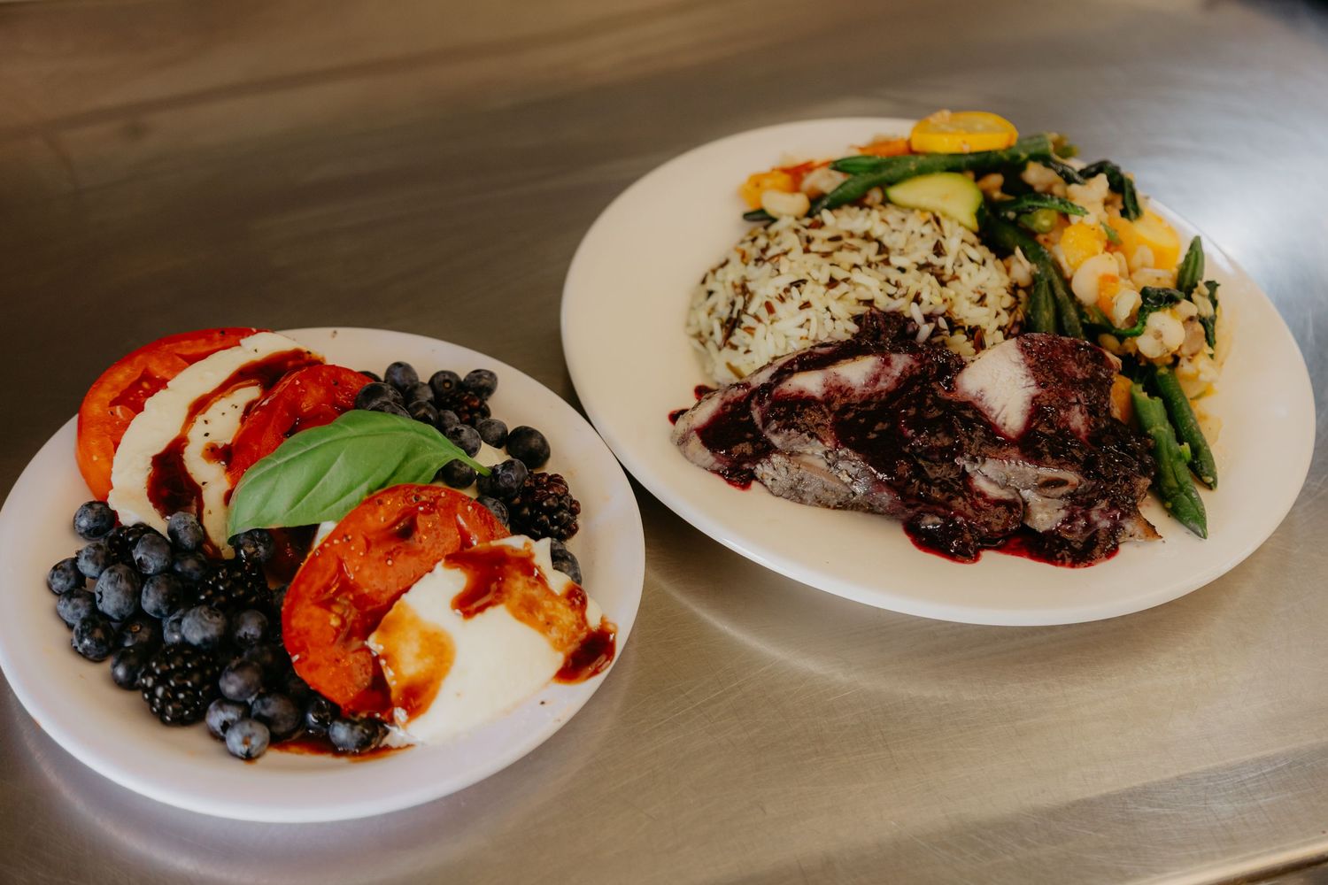 Multiple plates of colorful gourmet food served at a wedding reception.