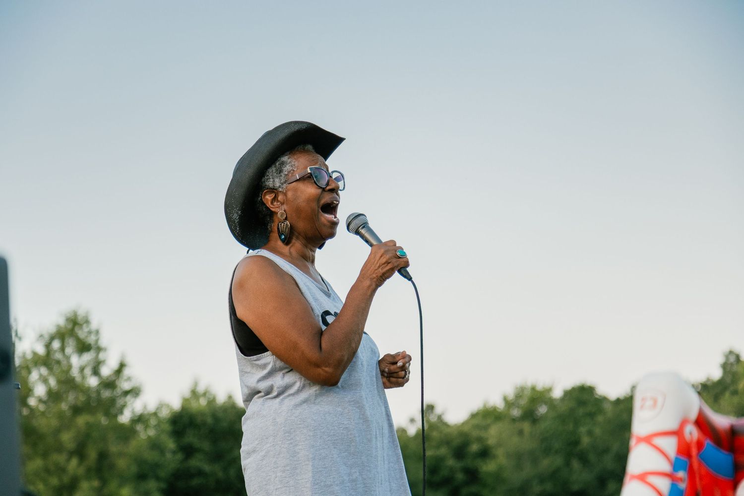 Performer singing on an outdoor stage during a summer event.