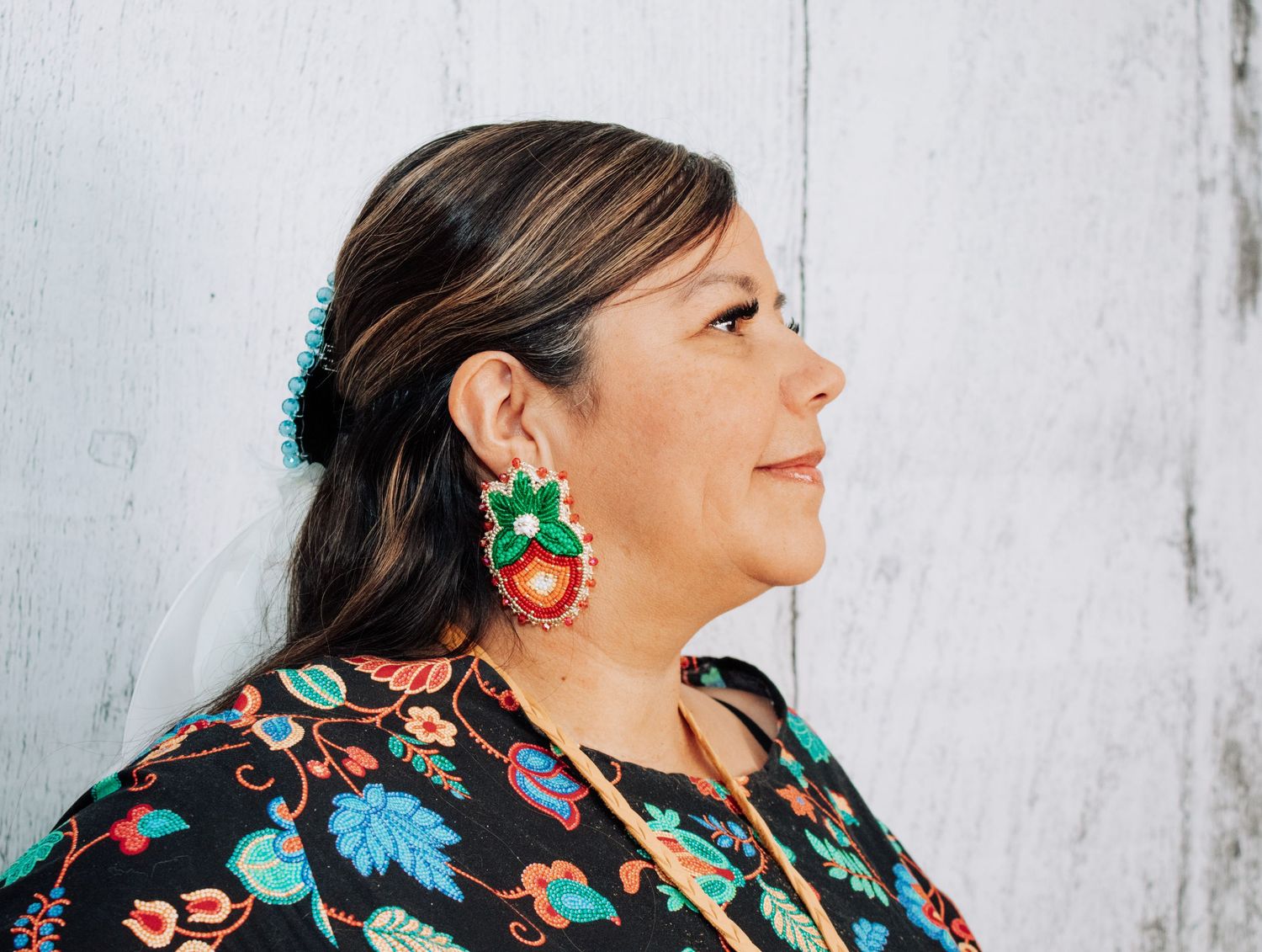 A profile view showing traditional Native American jewelry and floral patterned clothing.