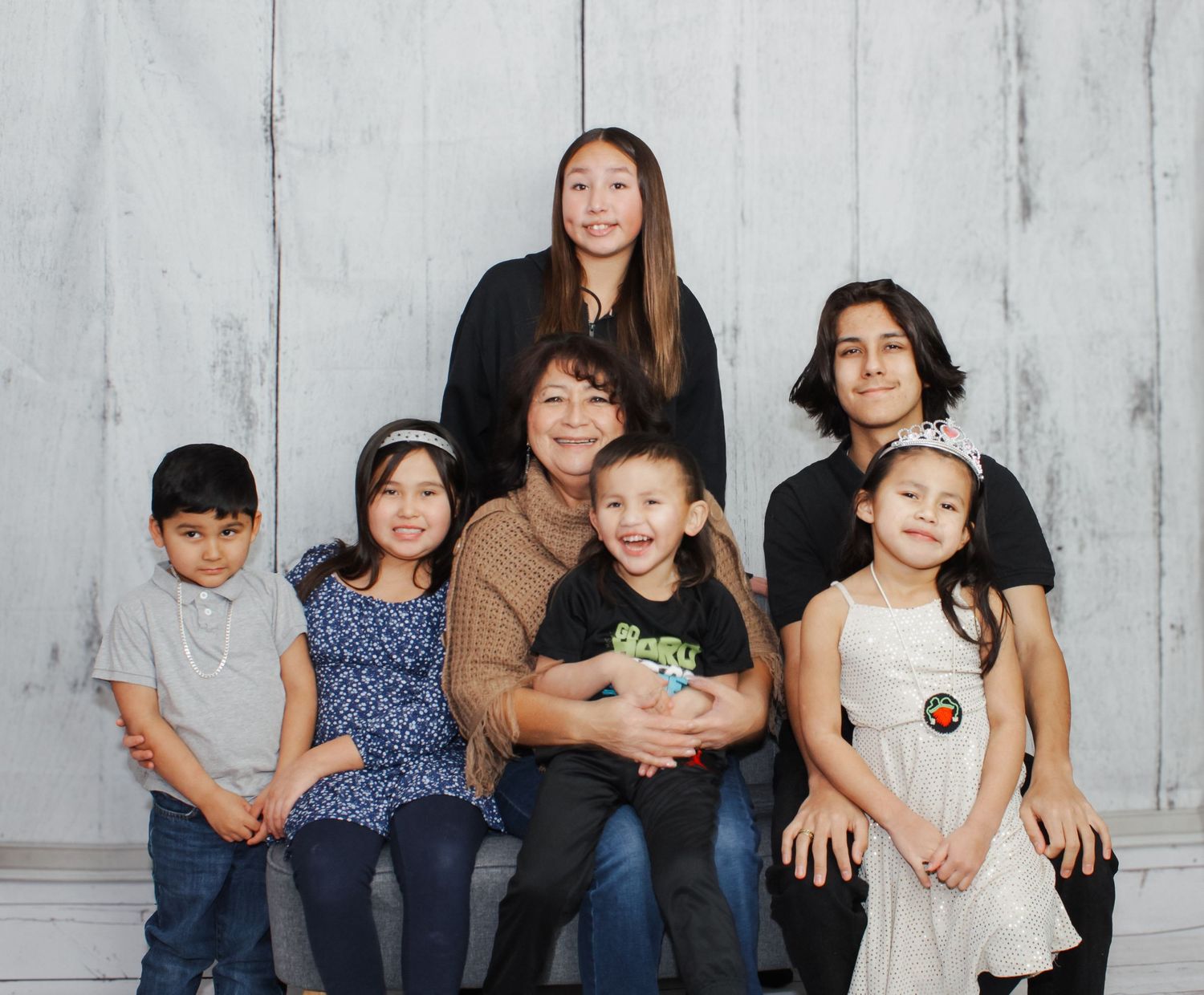 Extended family group photo with children and adults on light background.