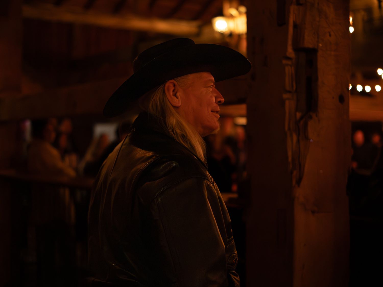 Performers in western attire silhouetted against warm lighting during an evening show.