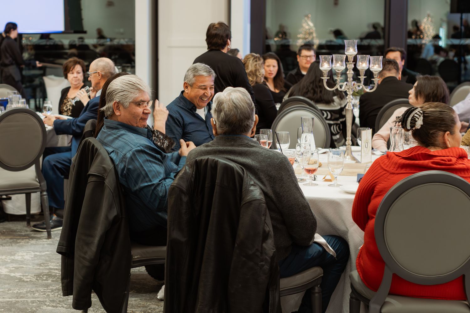 Guests seated at round tables during an indoor holiday celebration event.