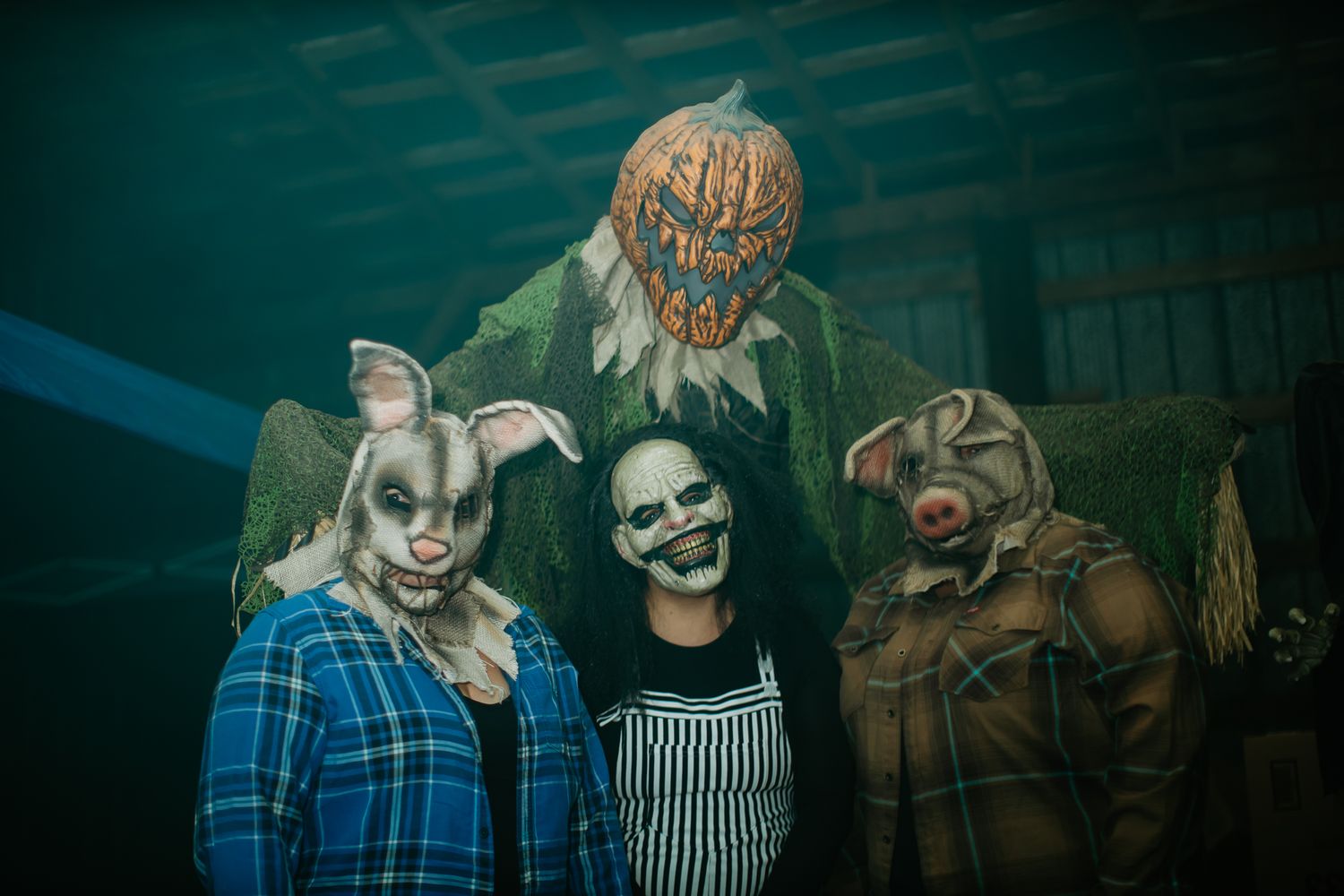 Halloween-themed group photo with spooky masks and blue atmospheric lighting.