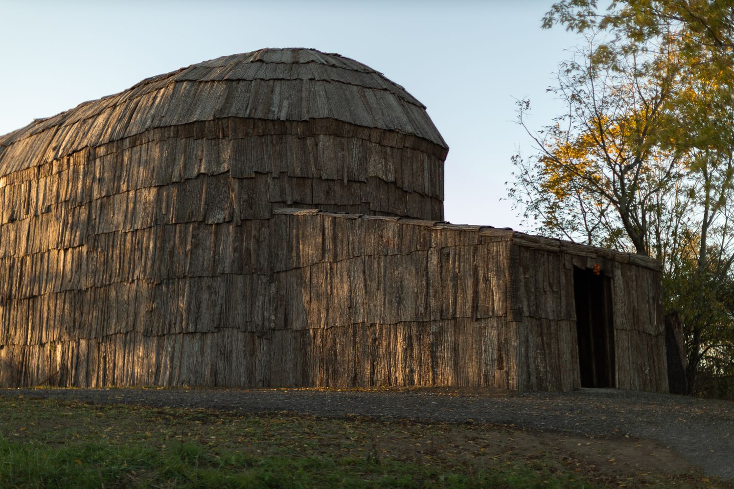 Panoramic view of traditional wooden longhouse structure with domed roof.