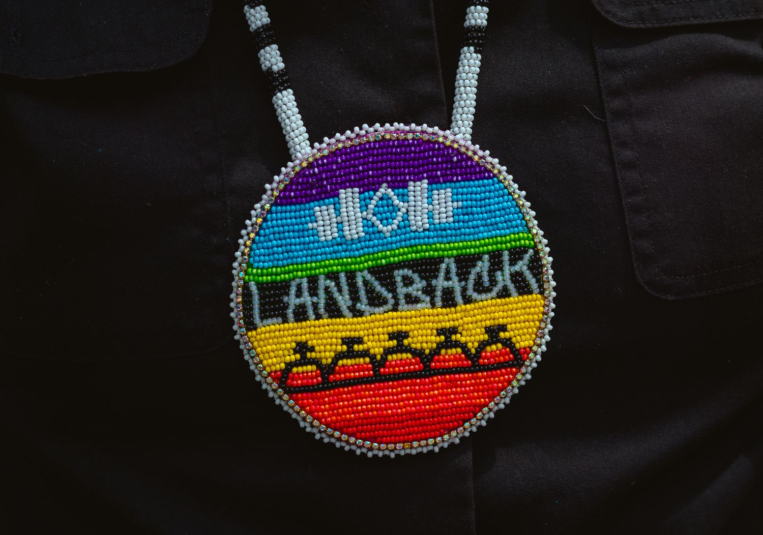 Colorful beaded medallions with indigenous designs displayed against a black background.