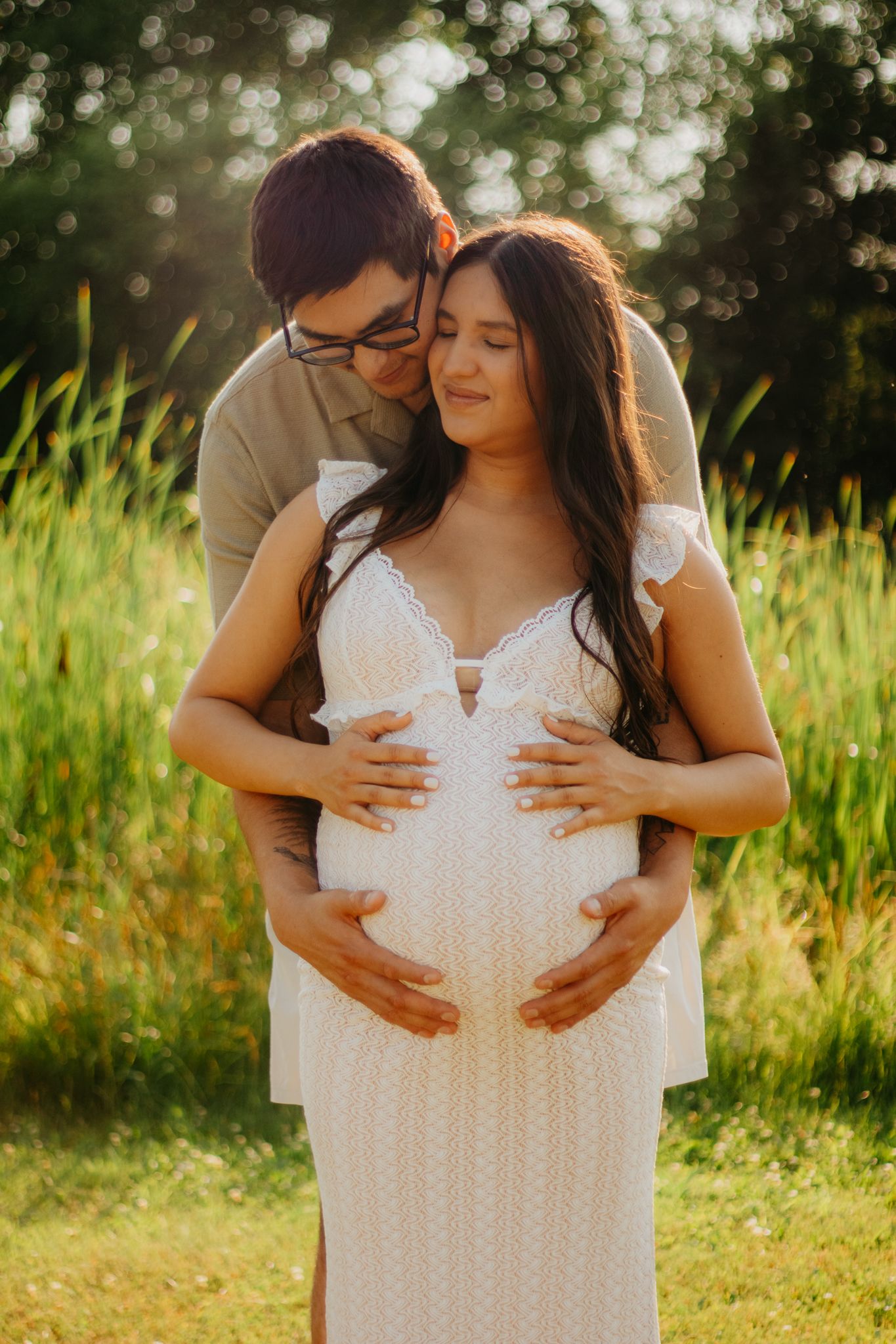 A tender moment captured in tall grass during golden hour.
