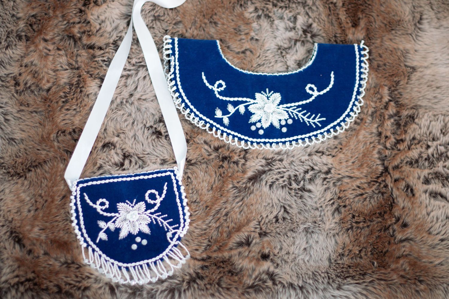 Handcrafted beaded accessories in navy blue with white floral embellishments displayed on textured background.