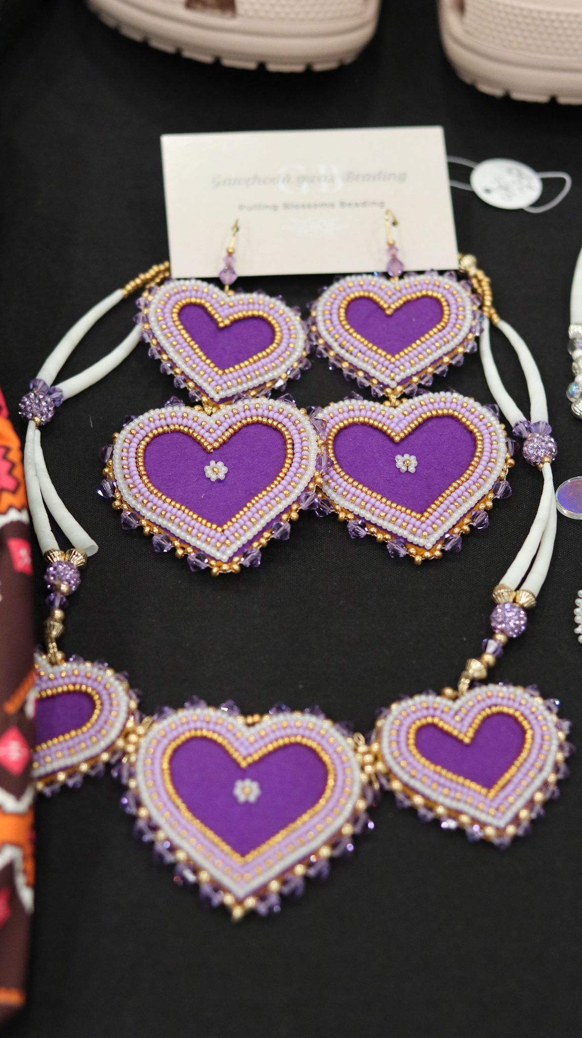 Purple beaded heart necklace and earring set with intricate seed bead design and crystal accents on display.