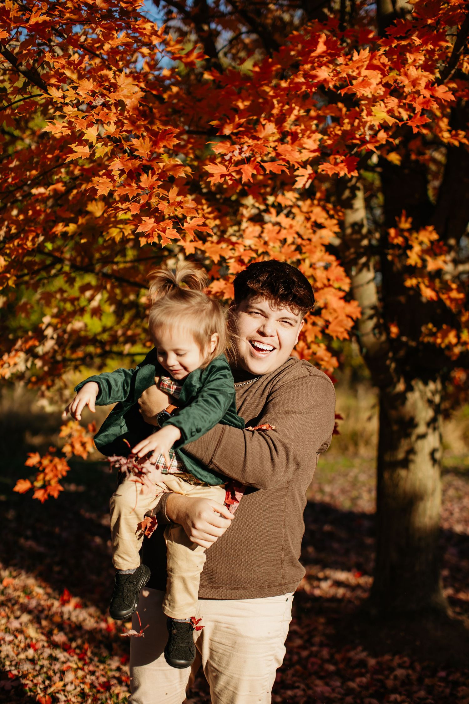 Playful outdoor portrait against bright orange autumn leaves.