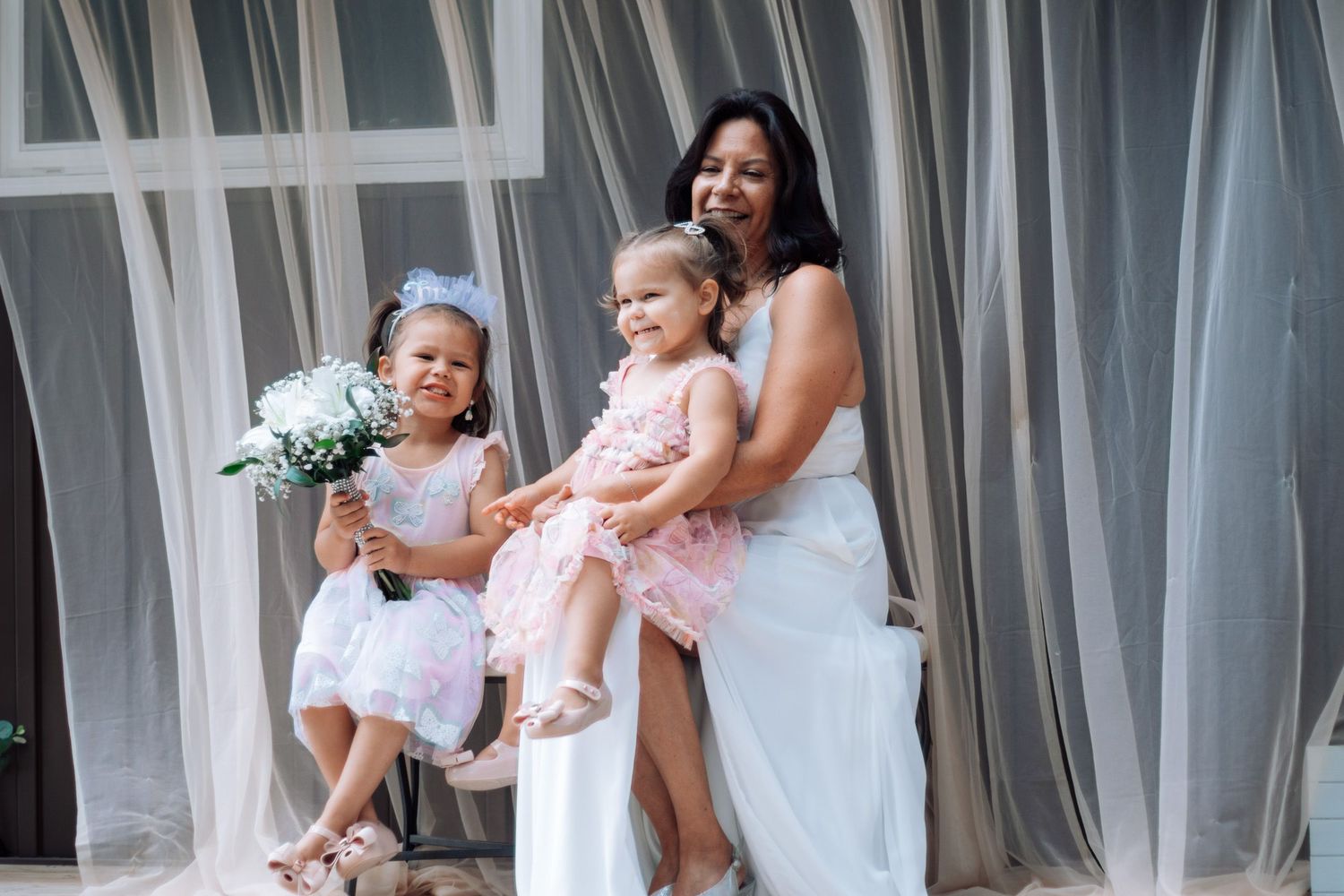 Young children in white dresses pose together during a wedding celebration.