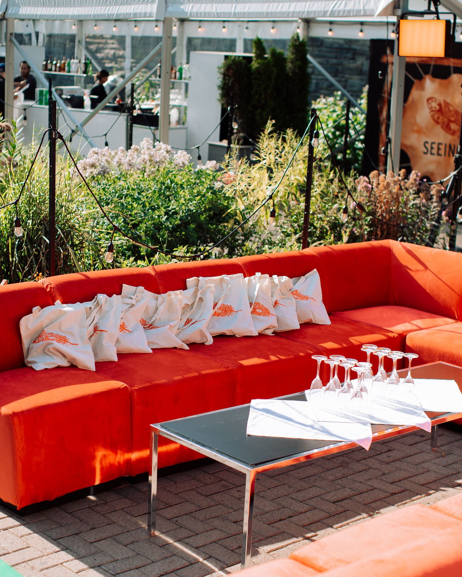 Outdoor event space with vibrant red sectional sofa, white pillows, and champagne glasses on modern coffee table.