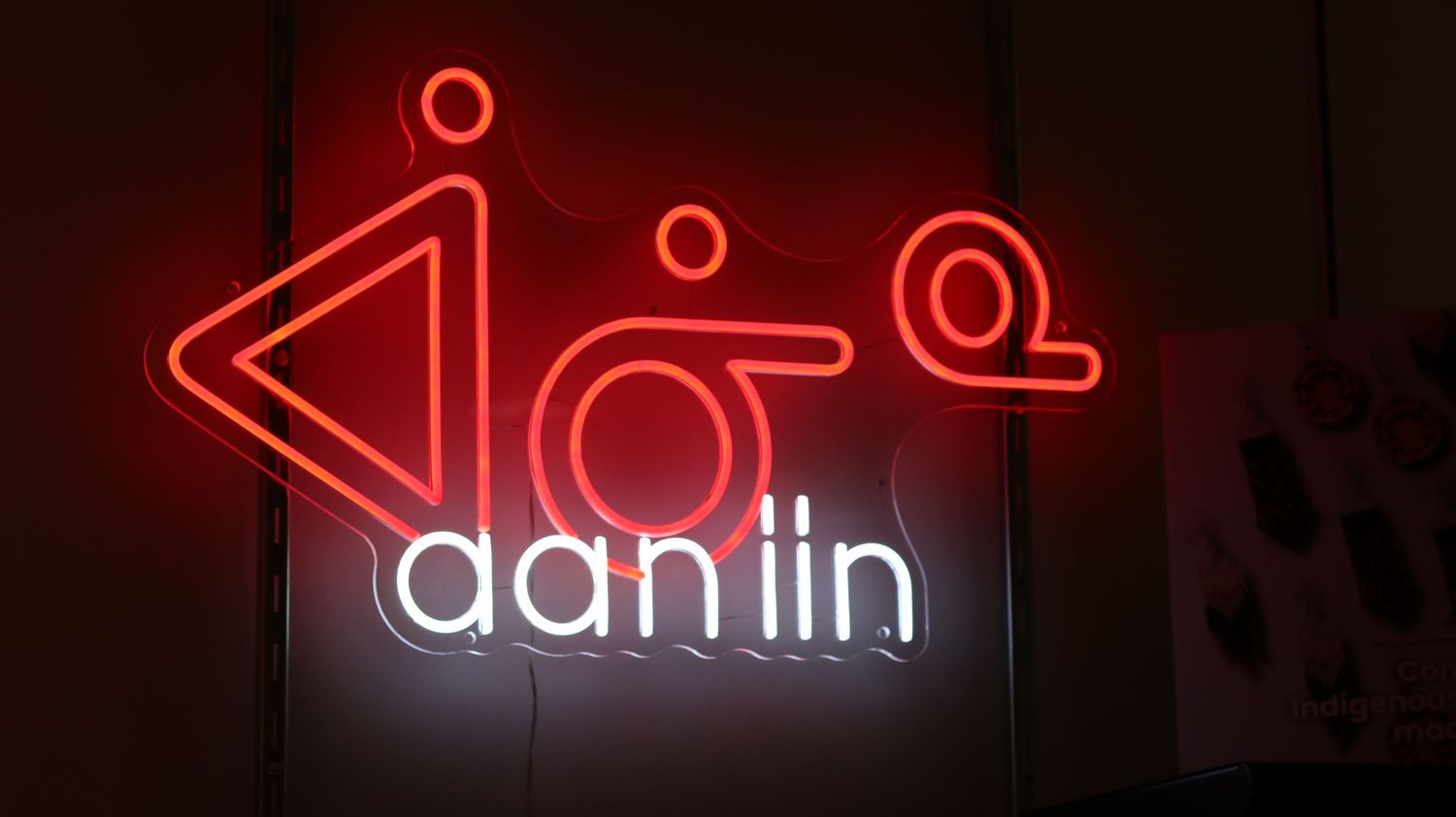Glowing red neon sign with abstract symbols and the text 'aan lin' displayed on a dark background.