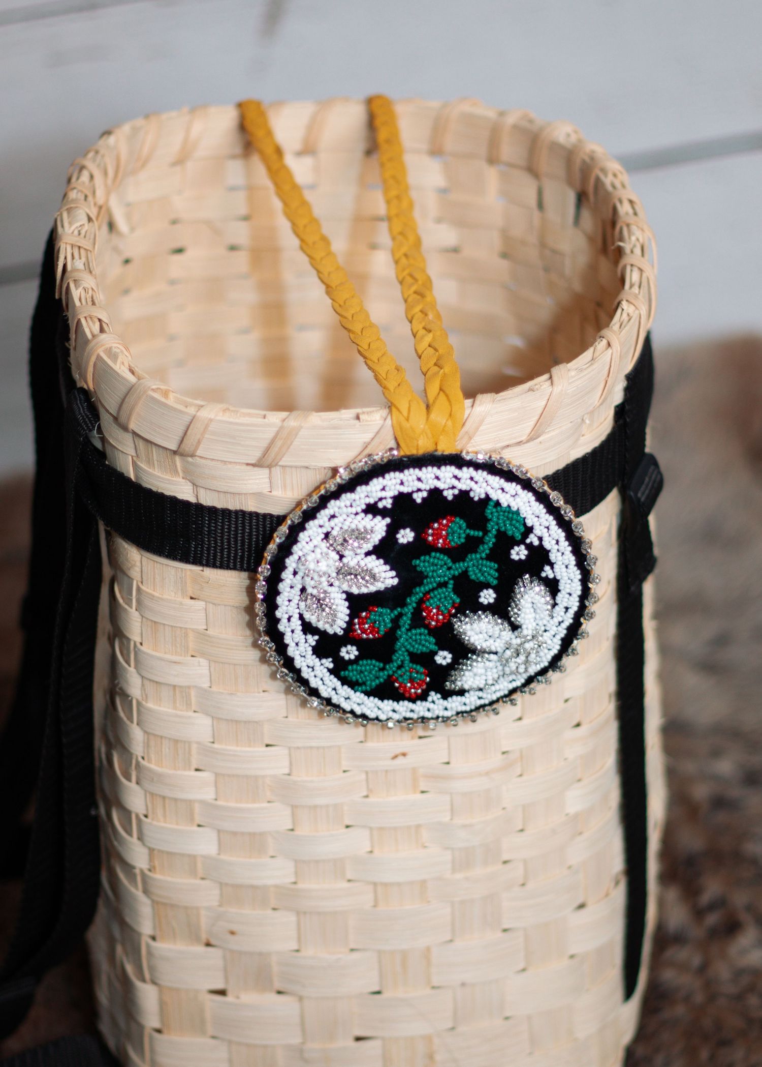 Handwoven basket with beaded decorative medallion featuring nature motifs.