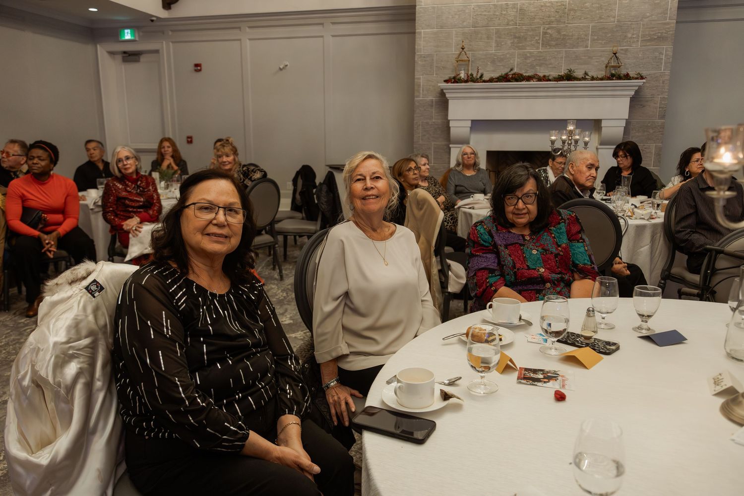 Guests enjoying a social gathering at decorated round tables in an elegant room.