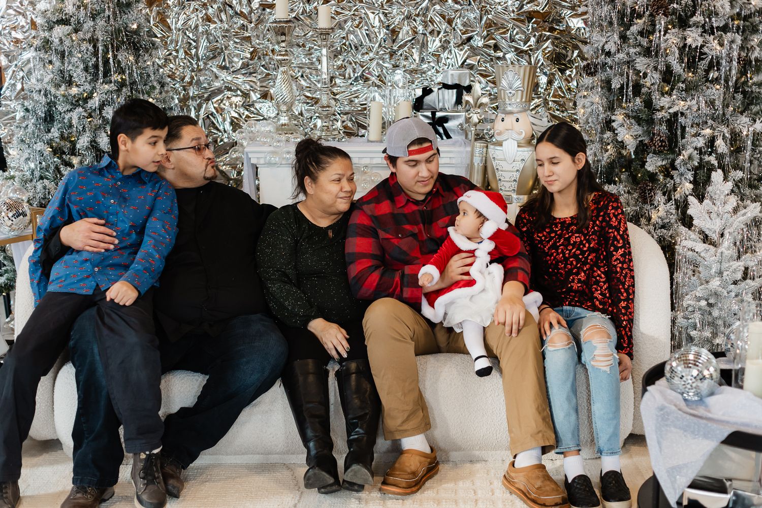 Winter family gathering captured in front of decorated Christmas tree with frosted branches.