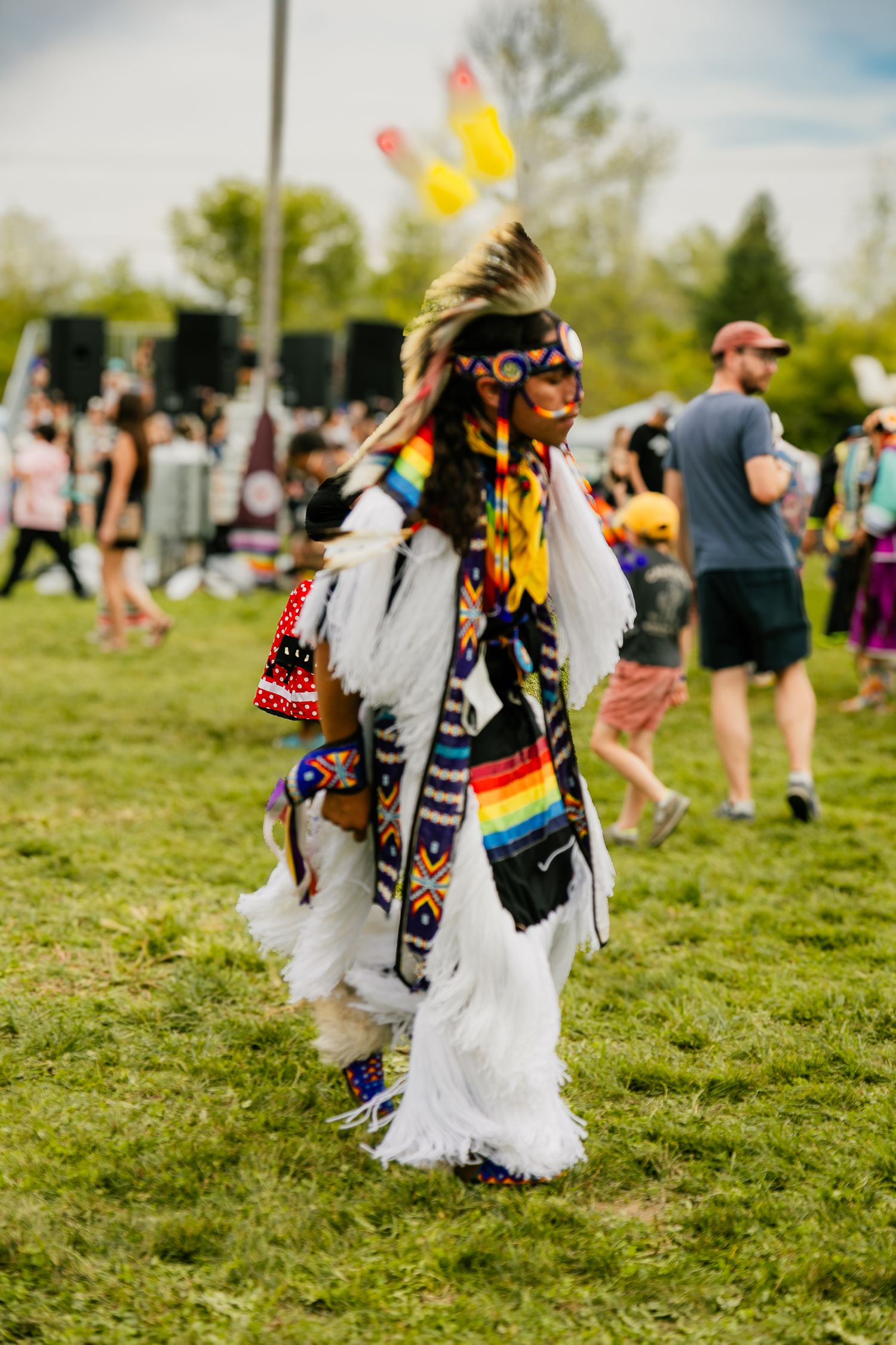 A performer in traditional Native American regalia dancing at an outdoor festival.