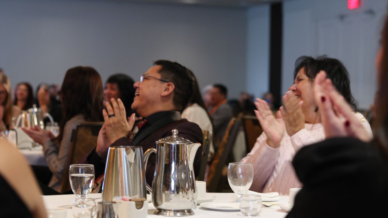 Conference attendees raising hands during an interactive session in a meeting room.