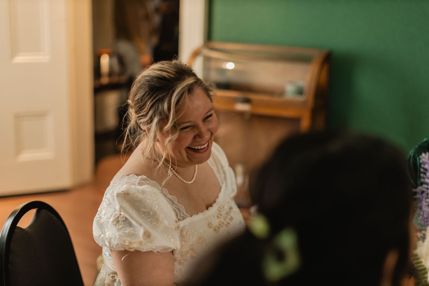 Joyful bride in a white lace wedding dress laughing during her wedding reception celebration.