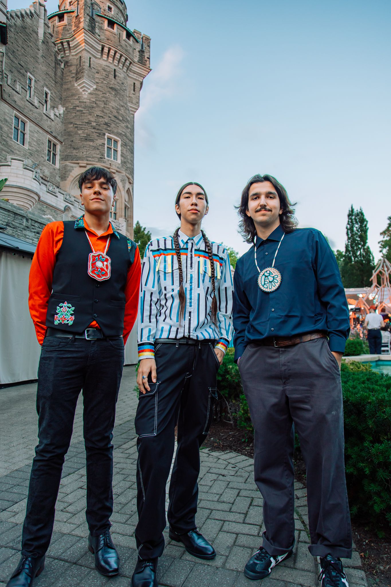 Group standing outside historic stone building wearing casual and formal attire.