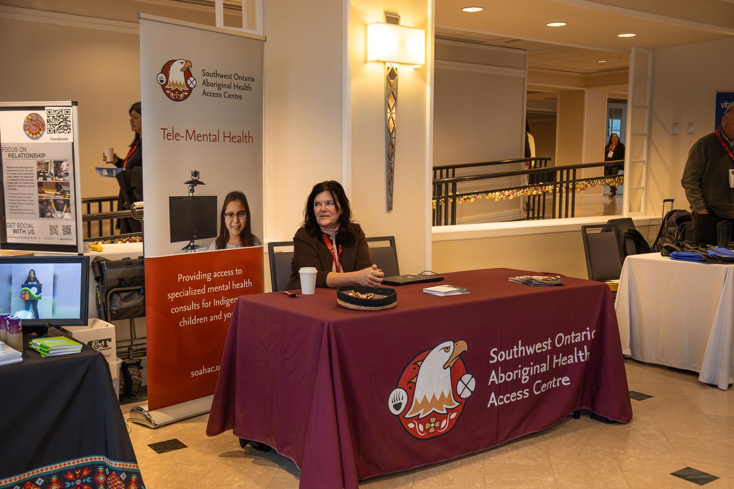 Information tables with burgundy tablecloths set up in a conference center lobby.