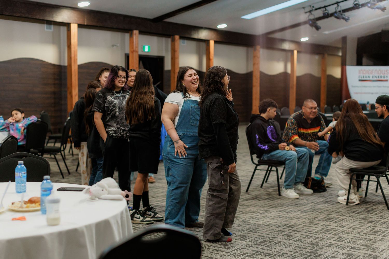 Diverse group of young Indigenous people socializing and networking at an indoor community event.