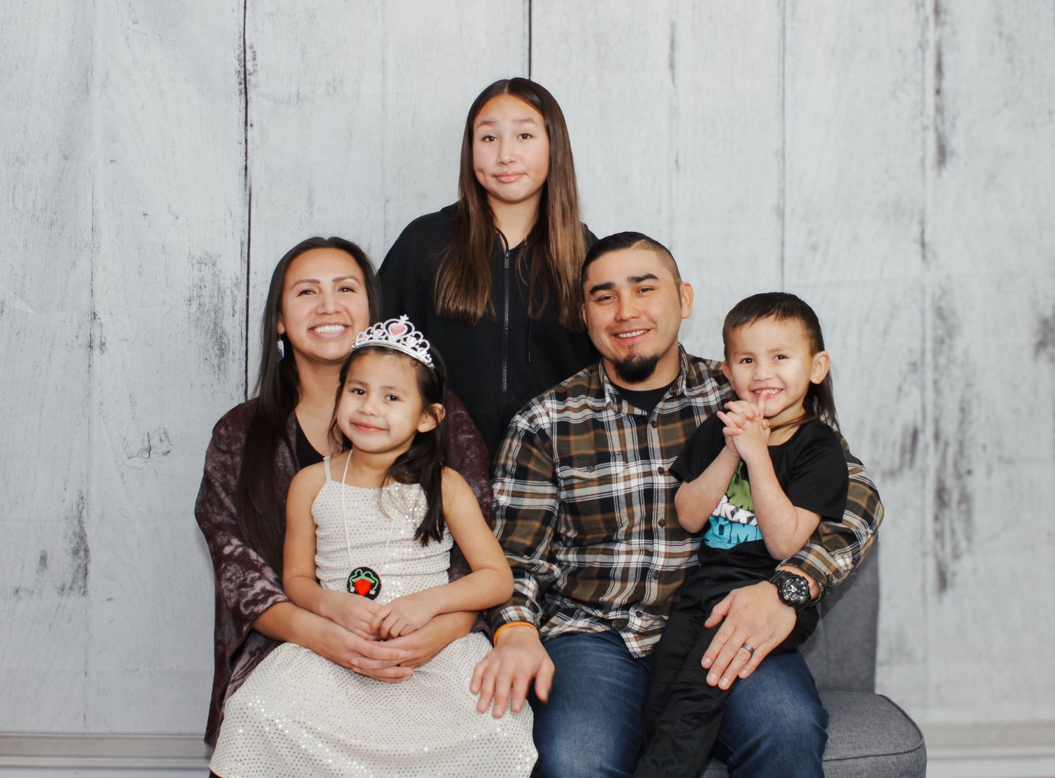 Panoramic family portrait showing multiple generations against white wall.