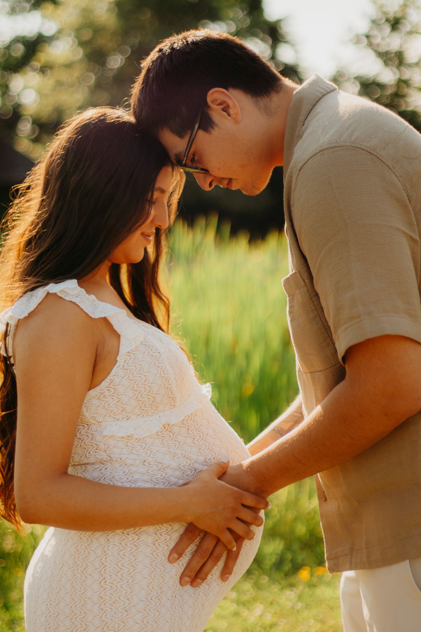 Side-view maternity photos showing affectionate moments between a couple at sunset.