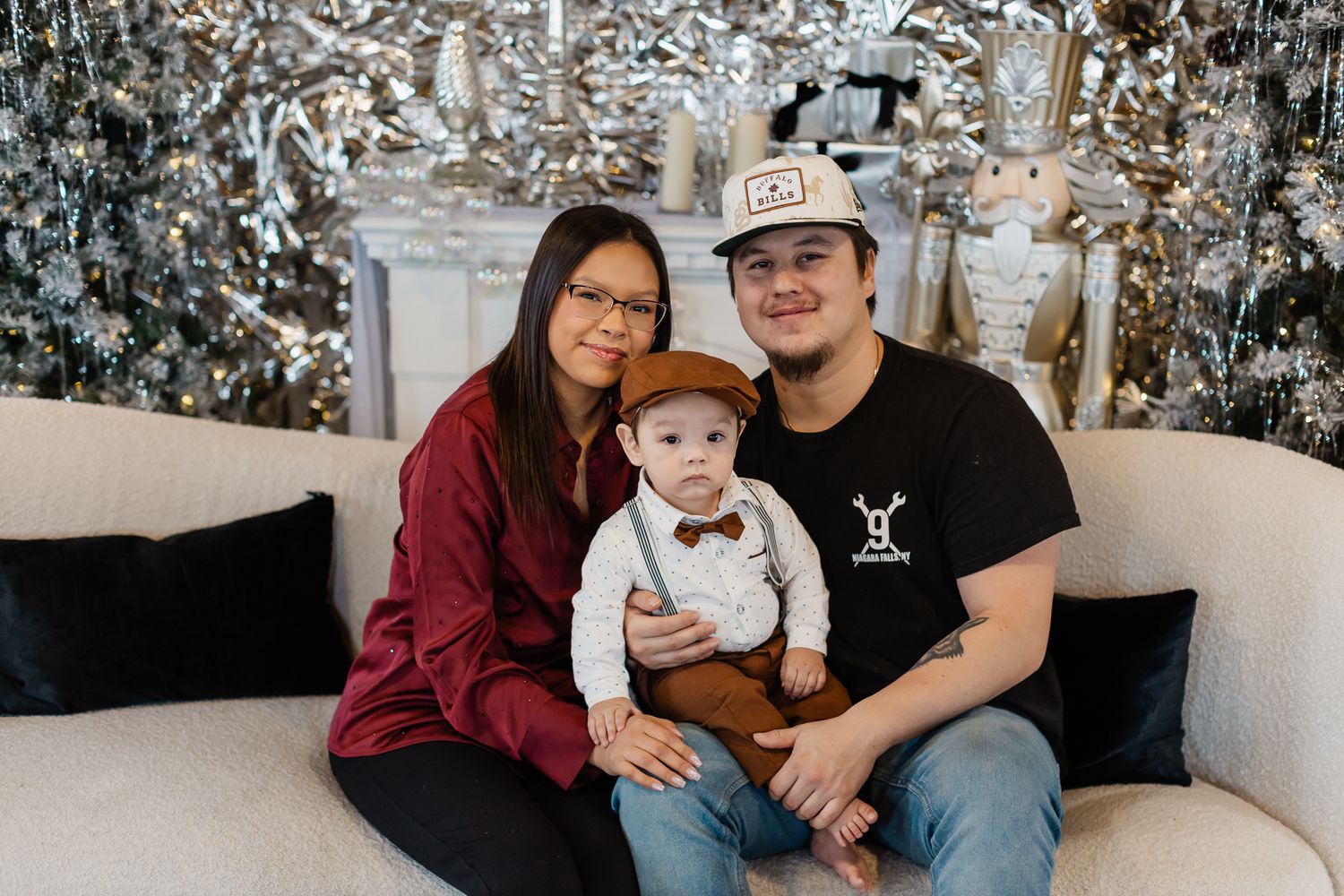 Family photo session with silver tinsel backdrop and coordinated casual outfits.
