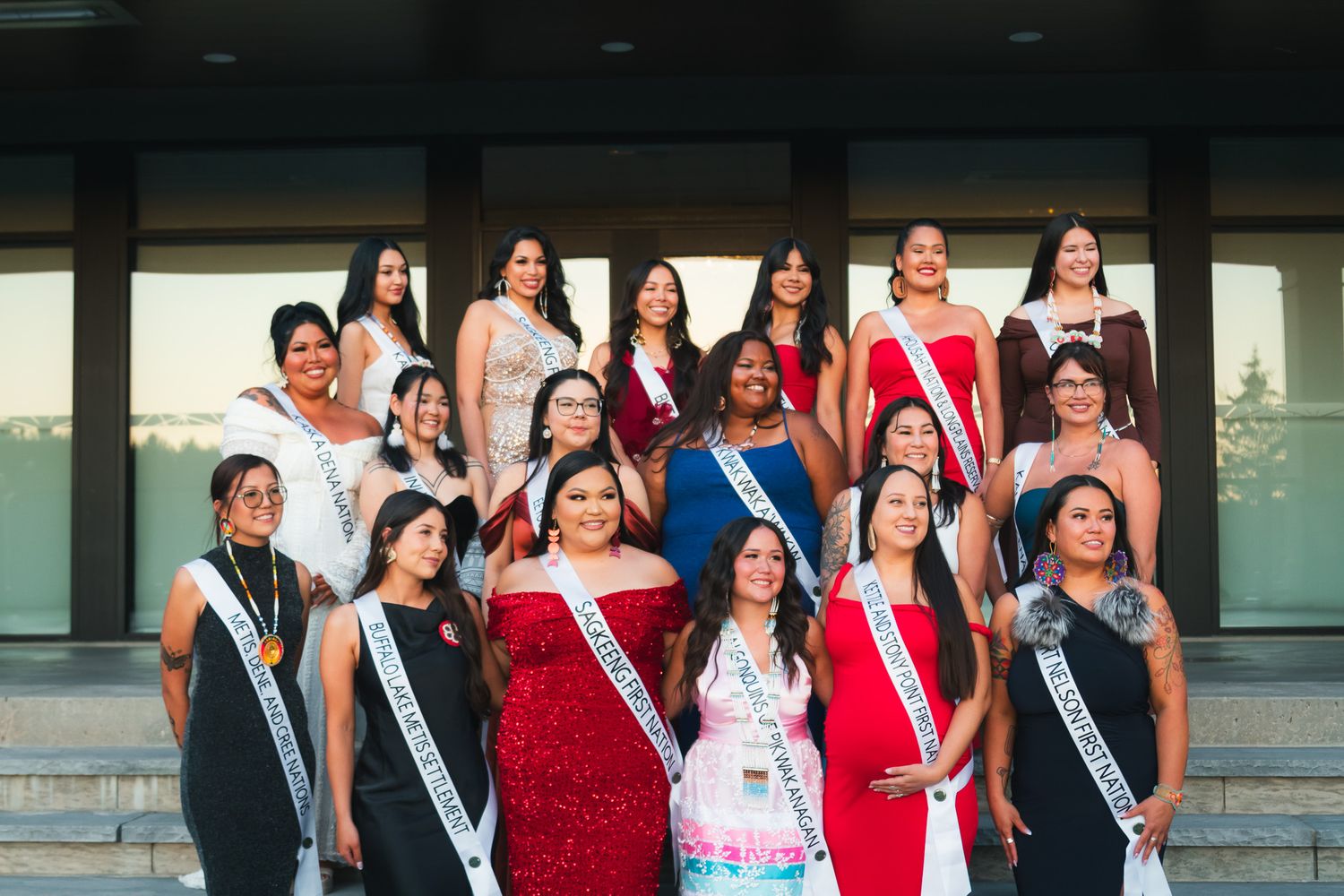Group wearing formal attire and sashes posing together indoors.