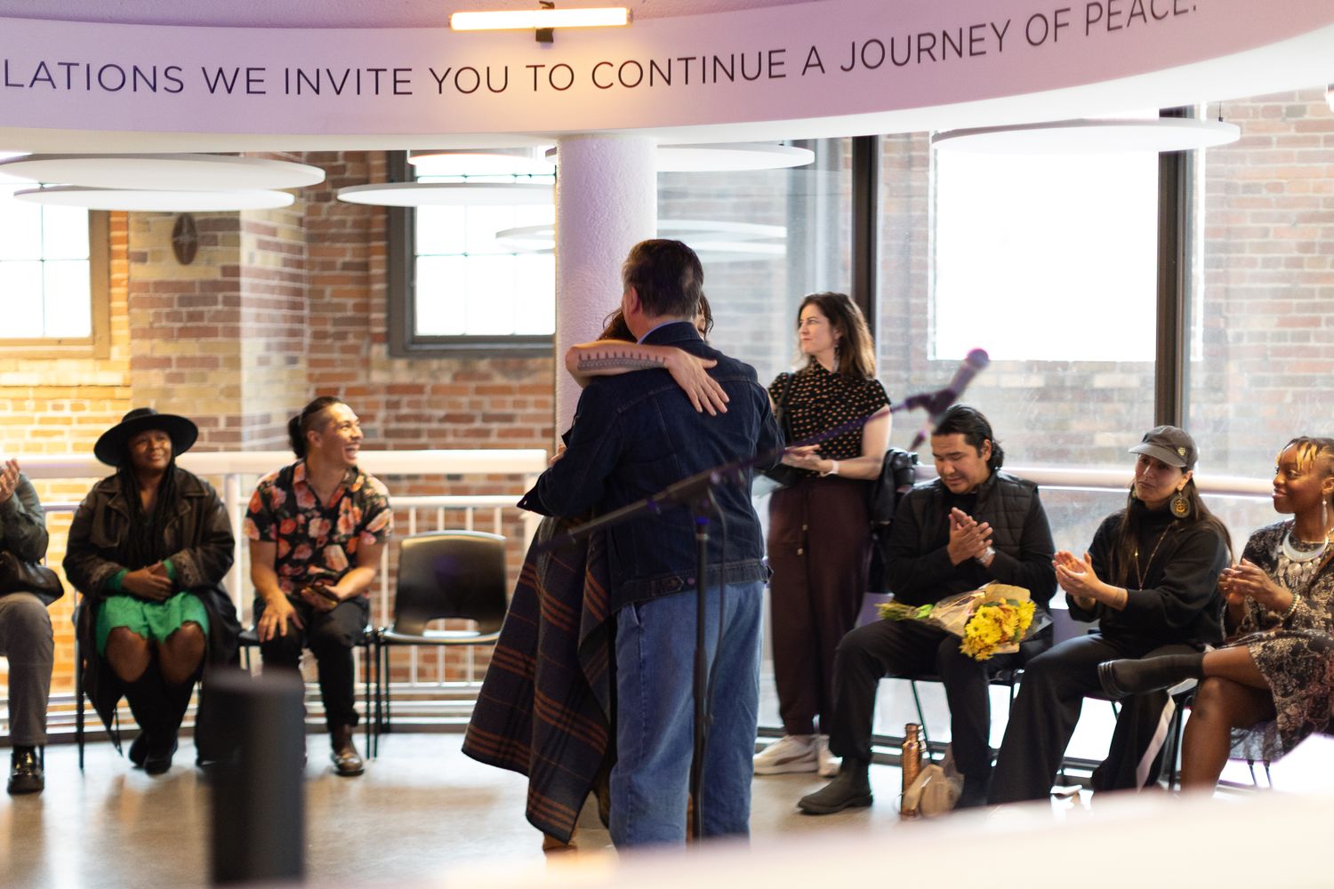 People mingling and socializing at an indoor event with brick walls and hanging lights.