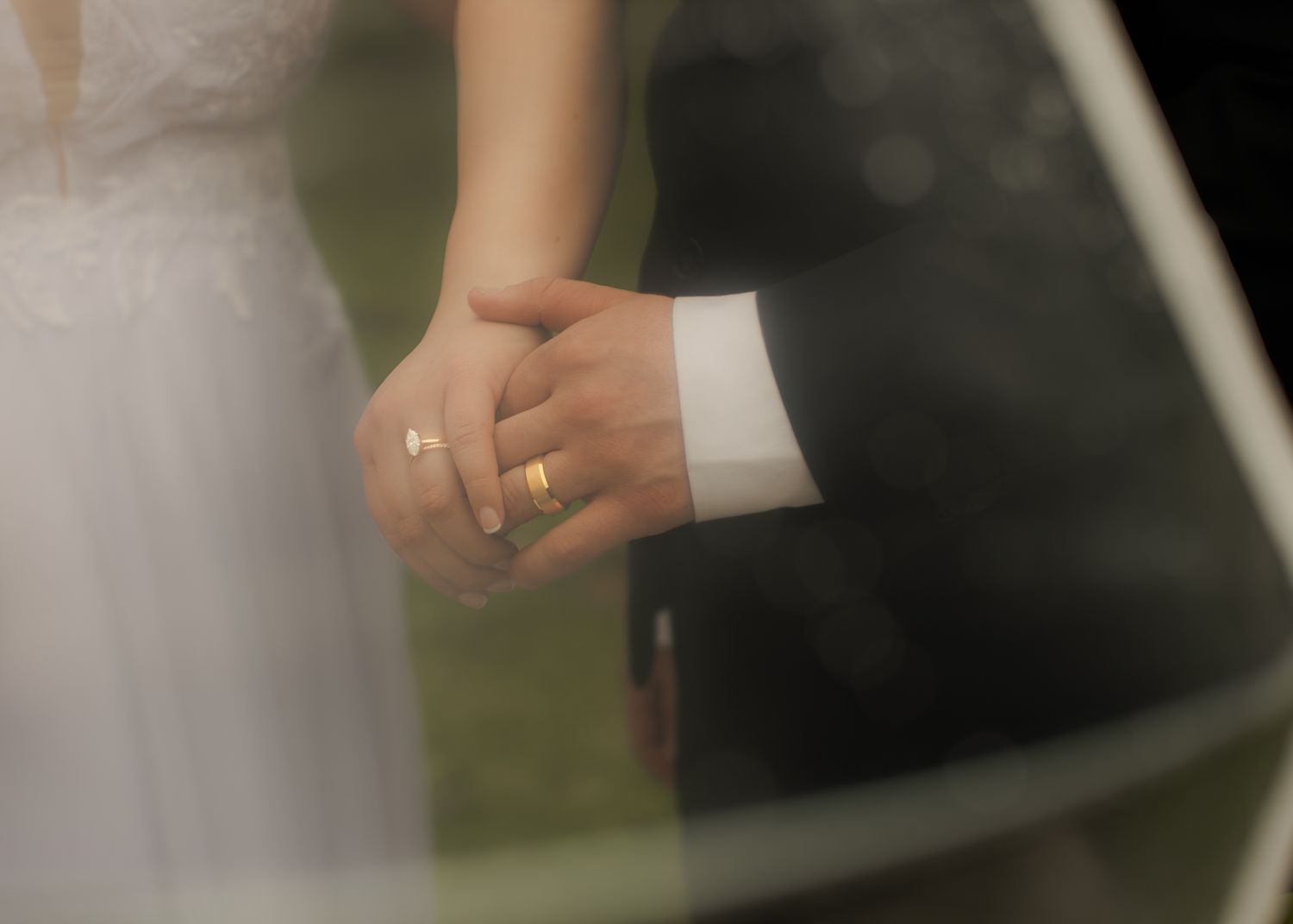 Close-up of newlyweds holding hands with gold wedding rings after marriage ceremony.