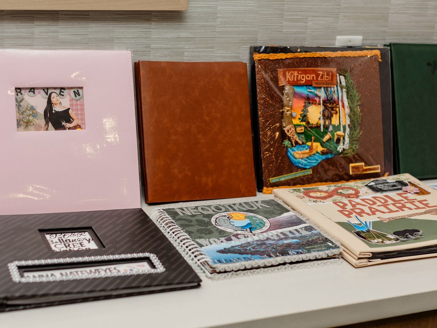 Collection of scrapbooks and photo albums displayed on a white table, including a pink album and leather-bound books.