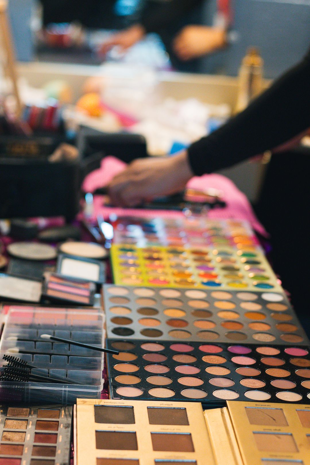 Colorful eyeshadow palettes and makeup tools arranged on a professional makeup artist's table.