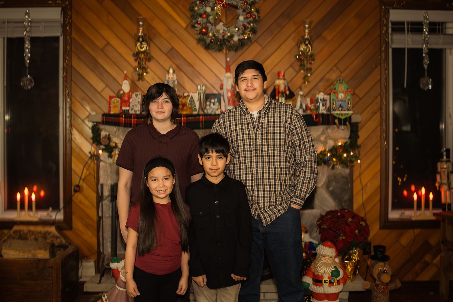 Holiday family portrait with Christmas decorations and warm wood paneling in background.