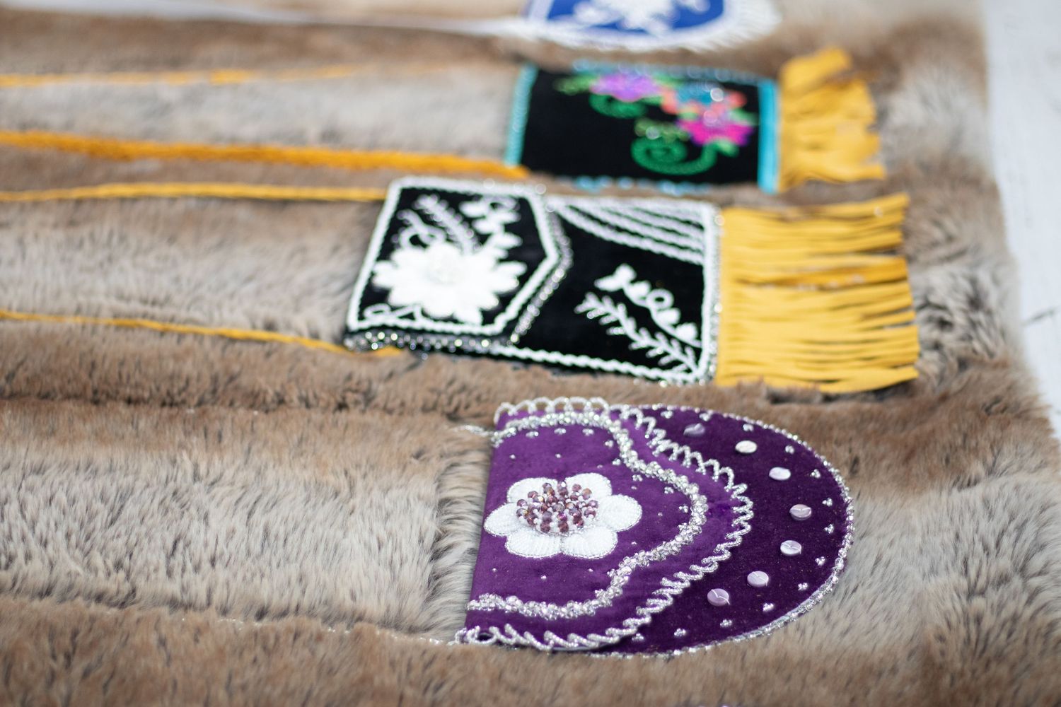 Close-up of beaded accessories with purple and black designs featuring yellow fringe details.