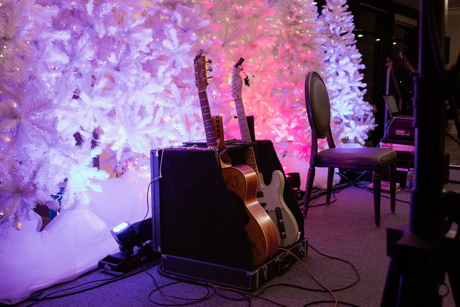 White Christmas trees illuminated with purple and pink lighting create a festive atmosphere.