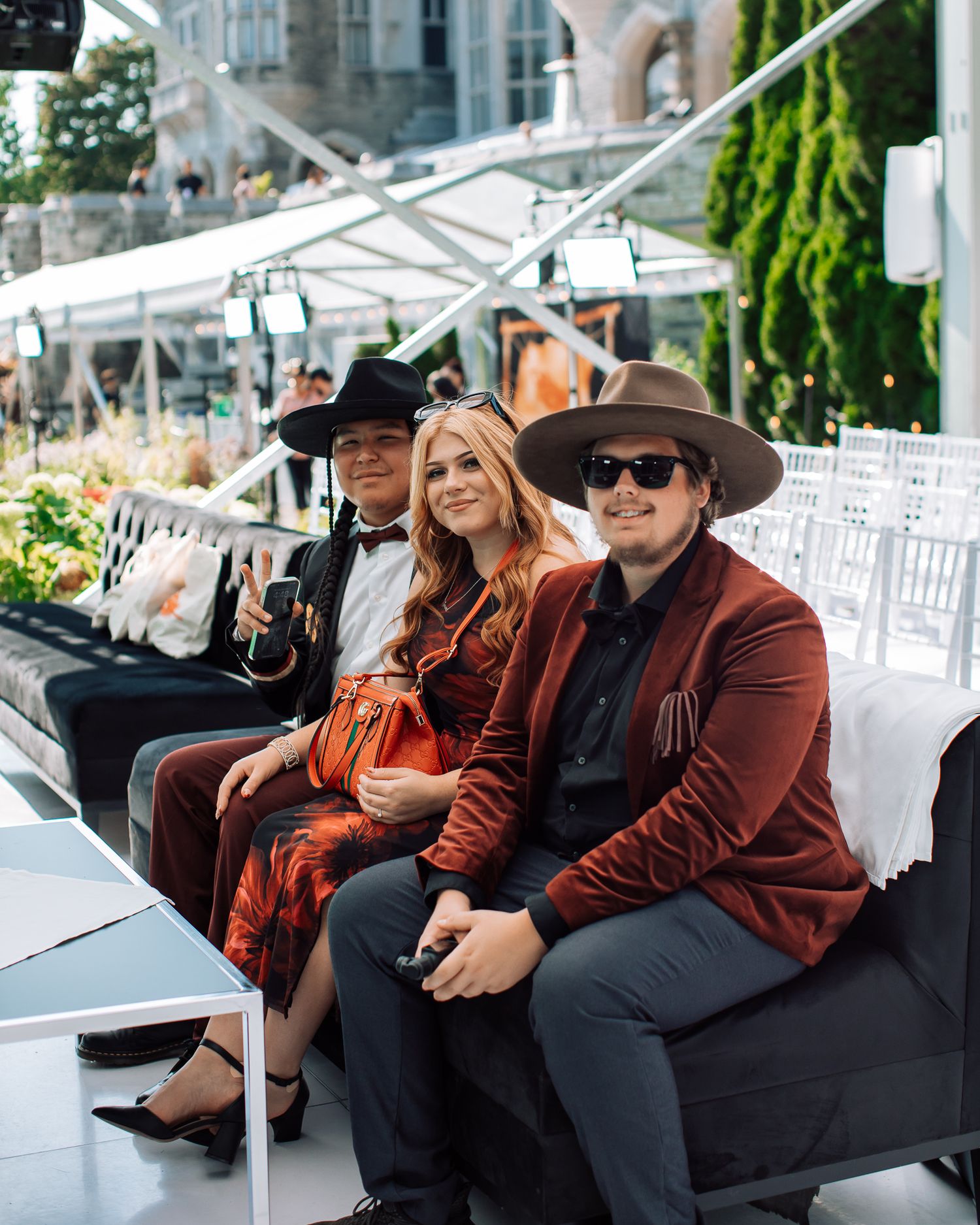 People lounging on black furniture at an outdoor event space under white tent.