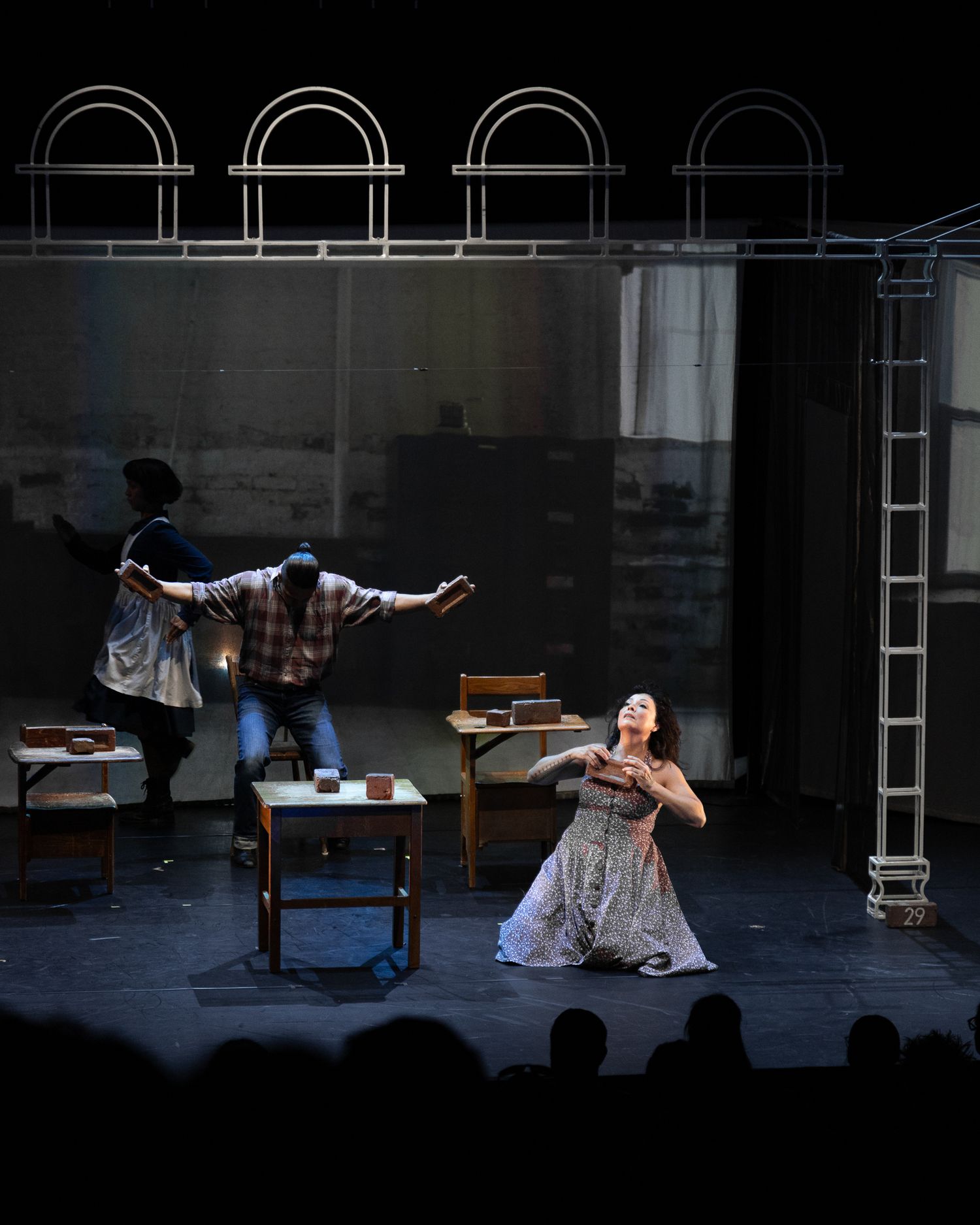 Theatrical performance showing dancers in dramatic poses on stage with minimalist set design.