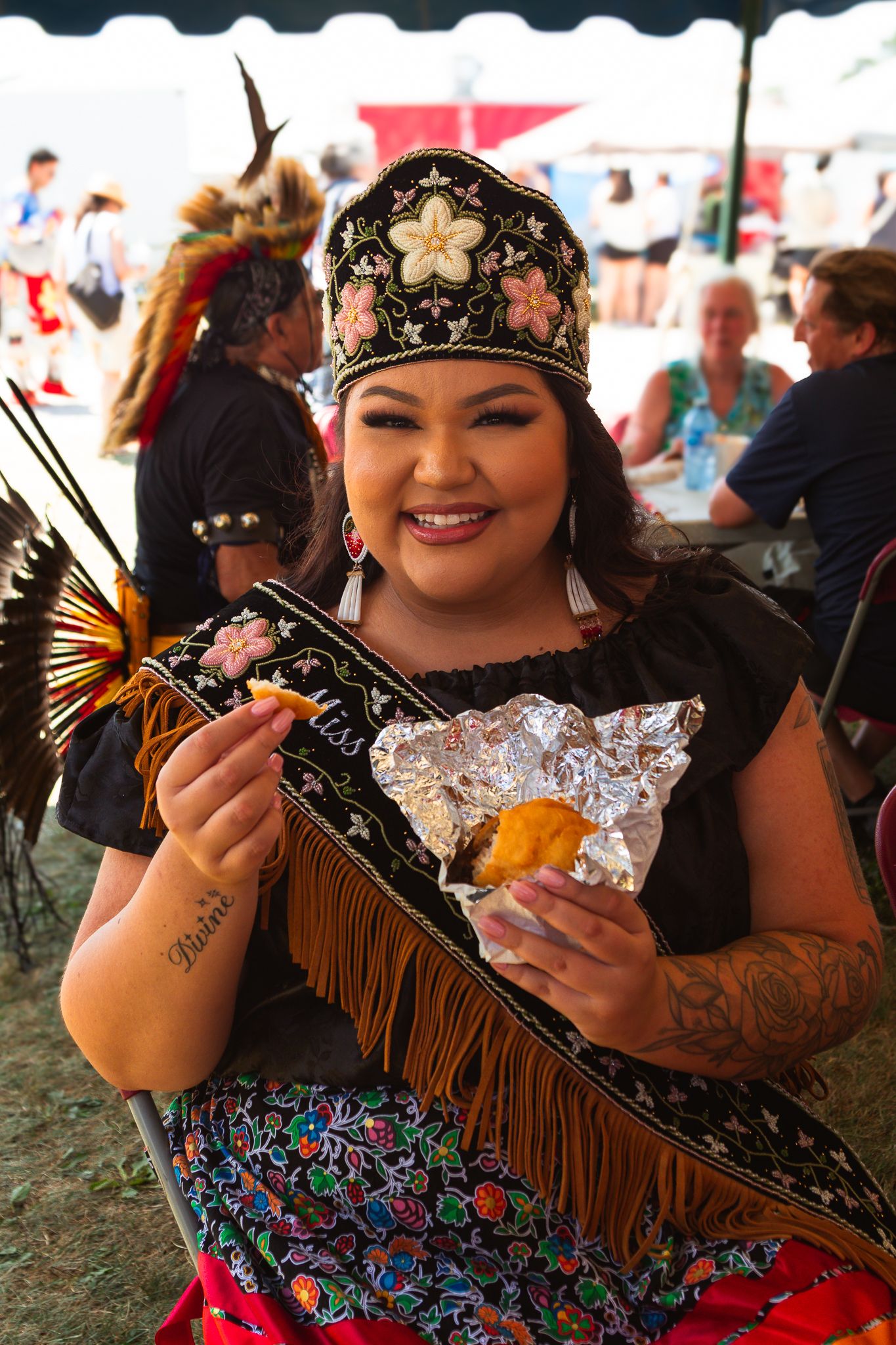 Festival attendee wearing native regalia and holding decorative items.