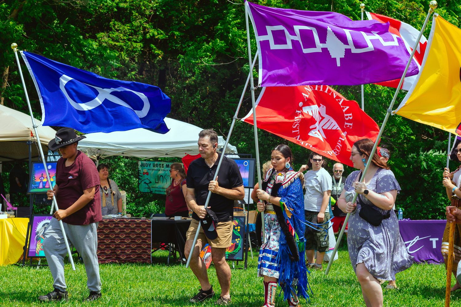 Outdoor festival with purple and rainbow flags waving in the breeze.