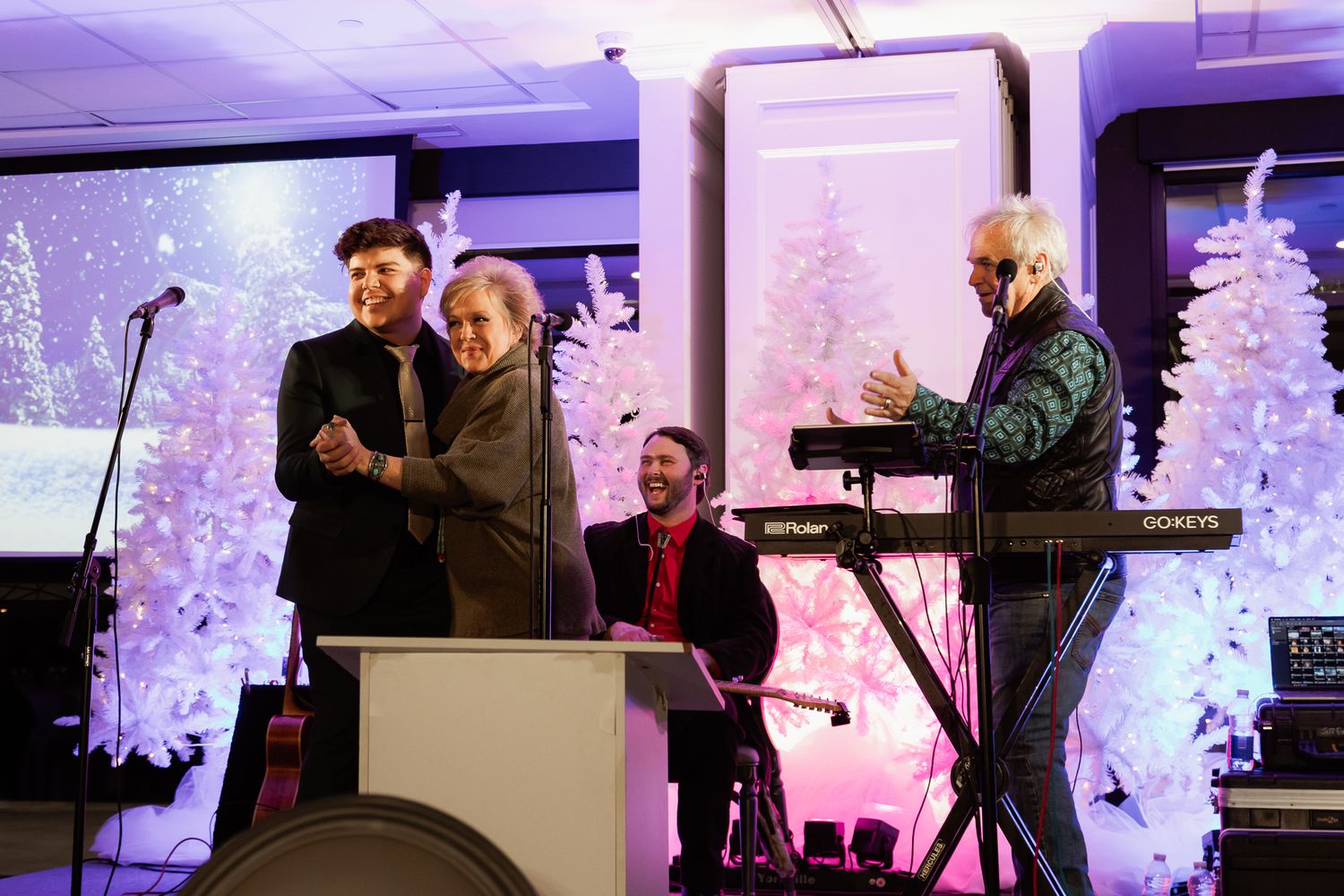 Event space with purple uplighting and white Christmas trees creating a festive atmosphere.