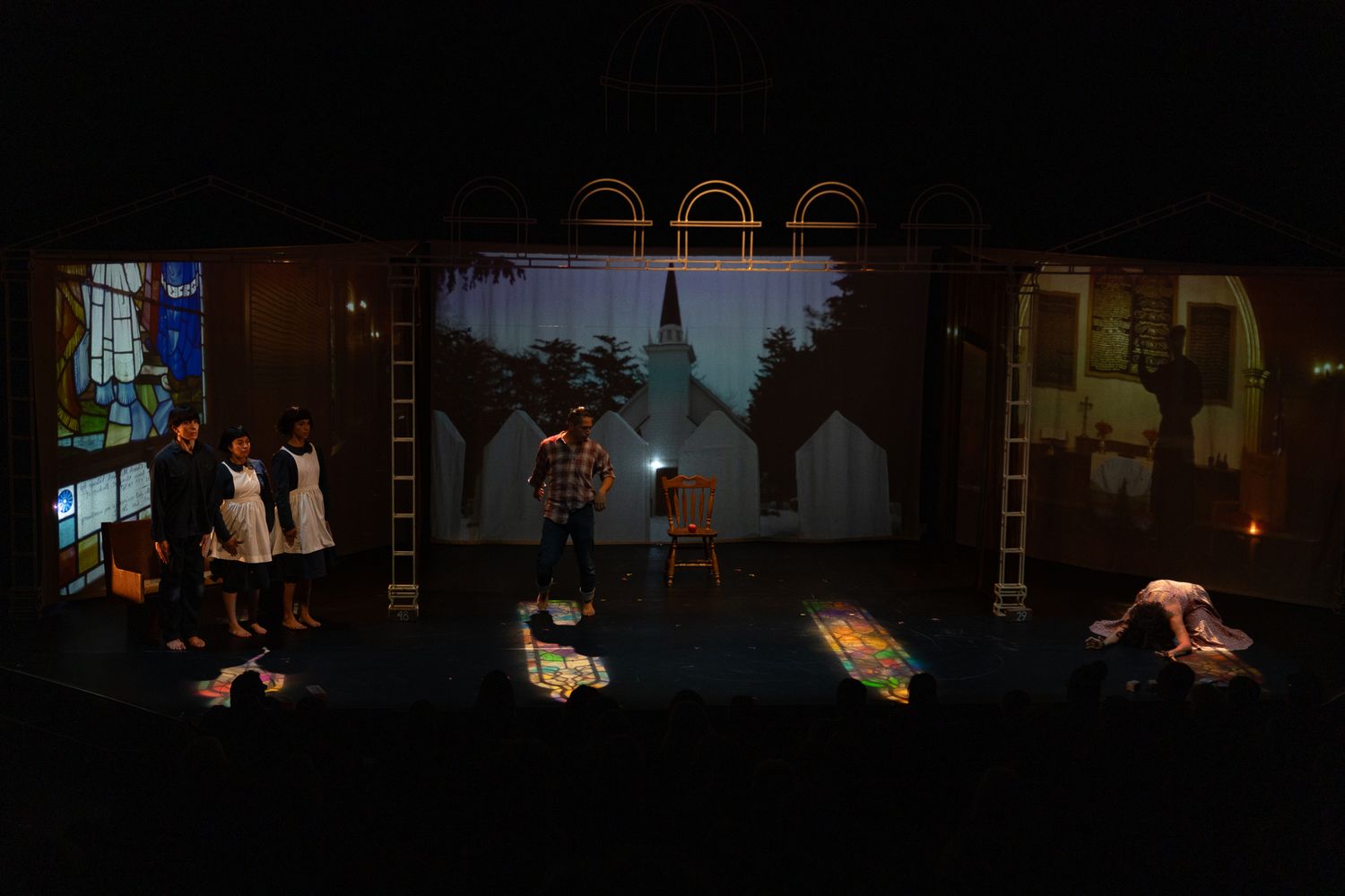 Theater stage production showing multiple scenes with dramatic lighting and silhouetted figures.