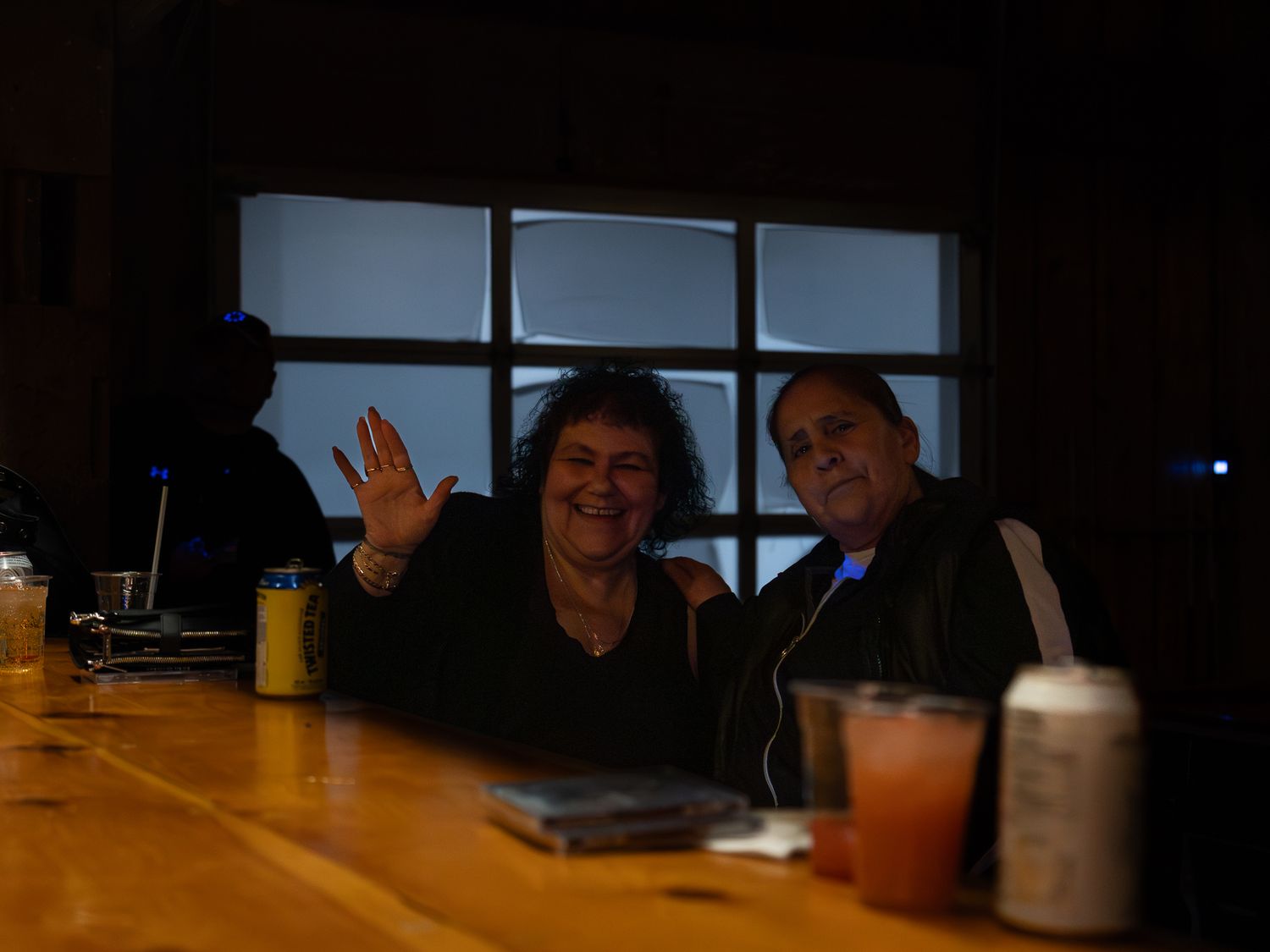 Silhouettes of people seated at a dark table with drinks having a conversation.