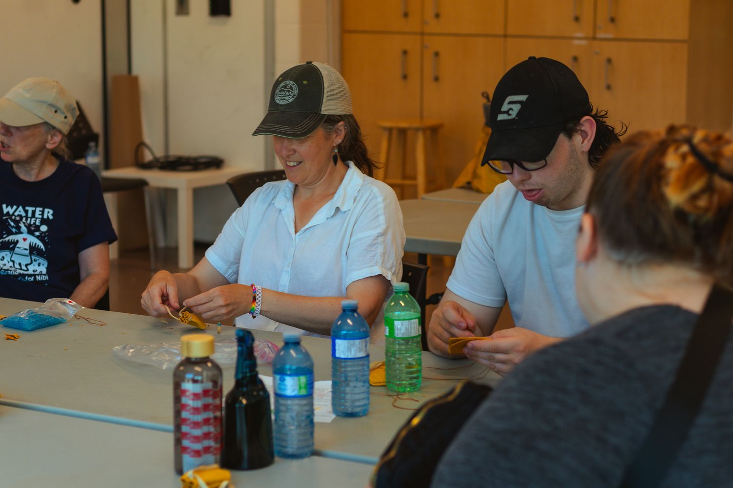 Students sitting at tables in a classroom setting with drinks and papers.