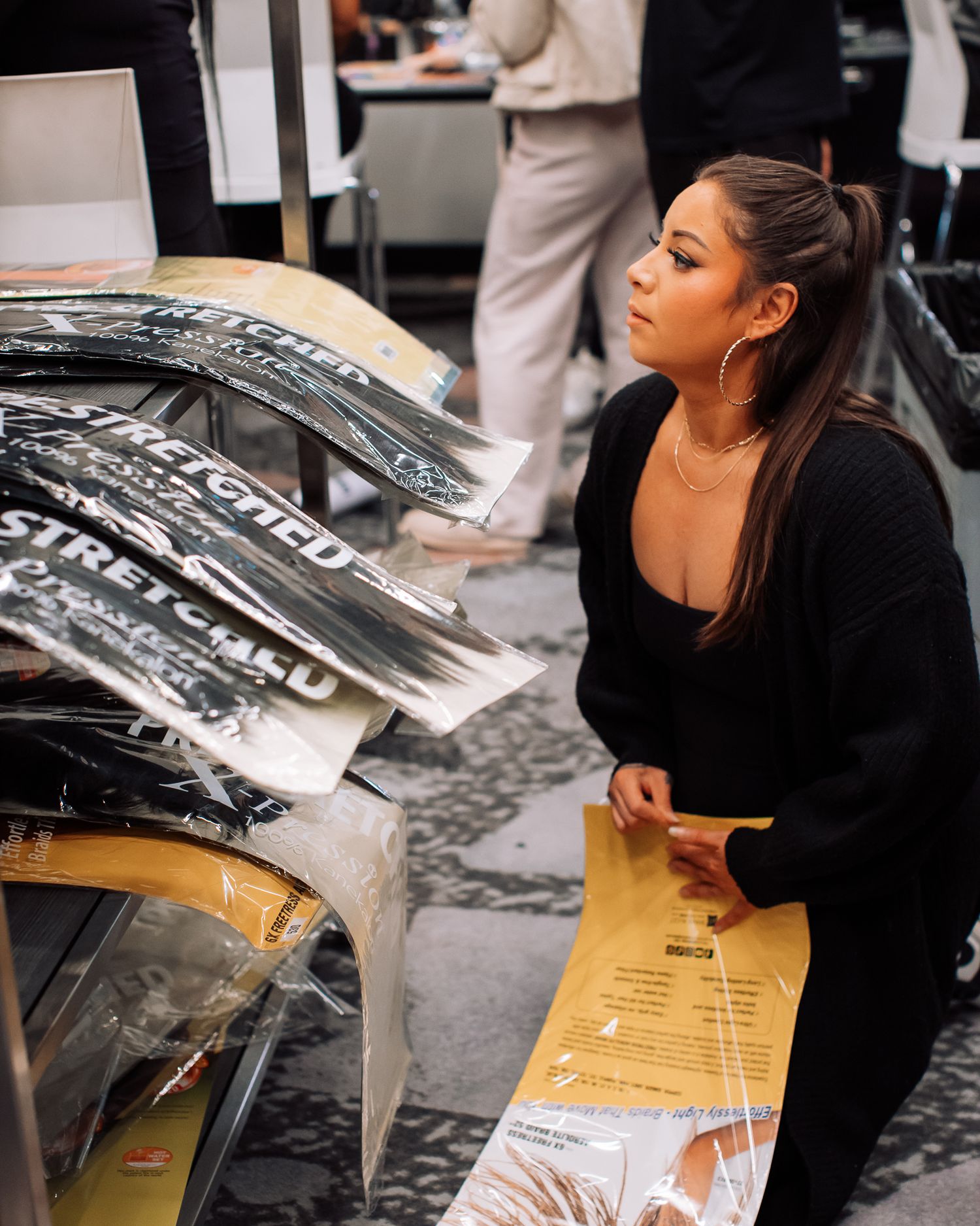 Woman in black outfit examines stretched car wrap signage at an automotive event.