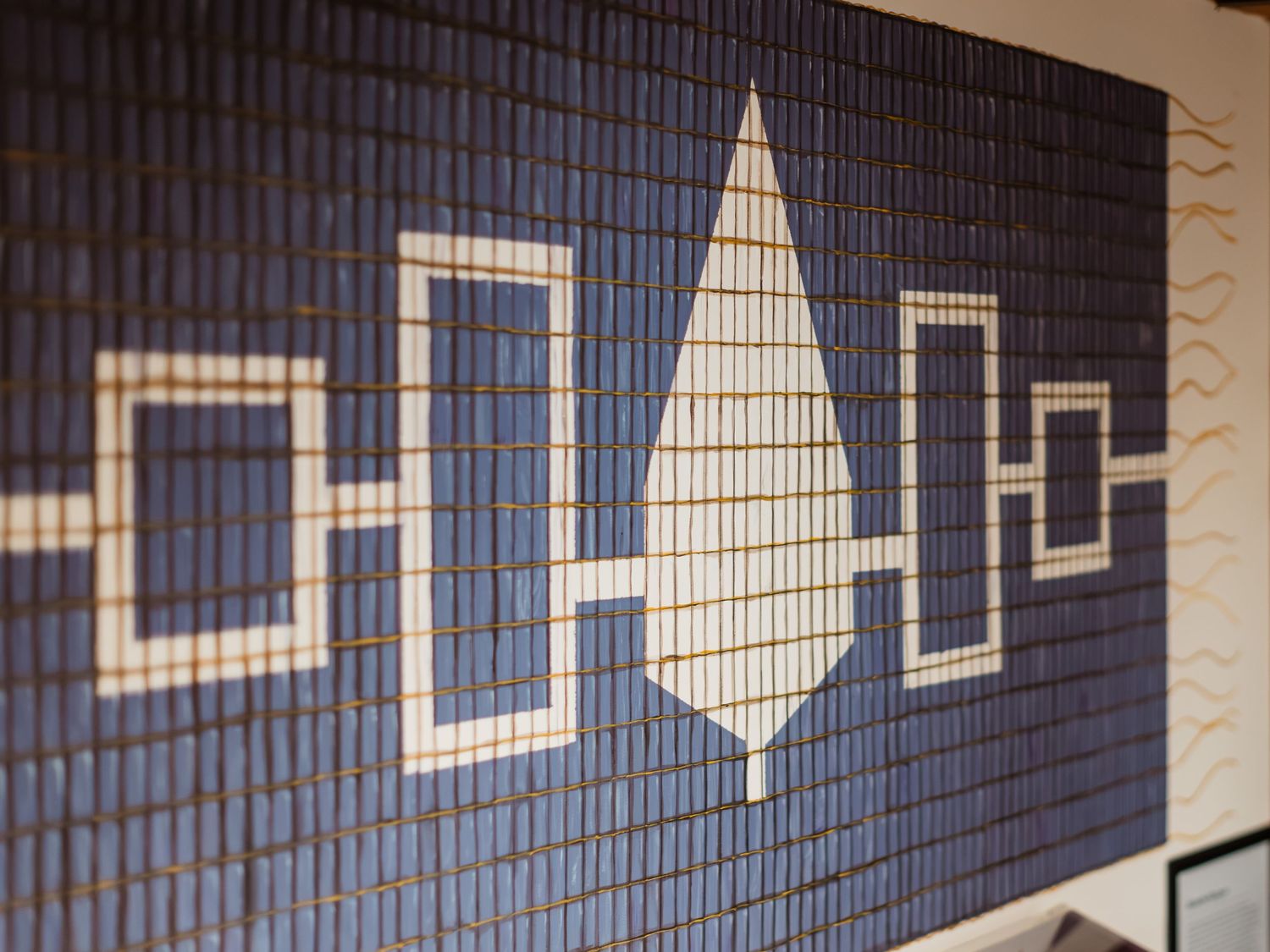 Blue mosaic tile wall art featuring geometric shapes and a white teardrop design in a modern decorative pattern.