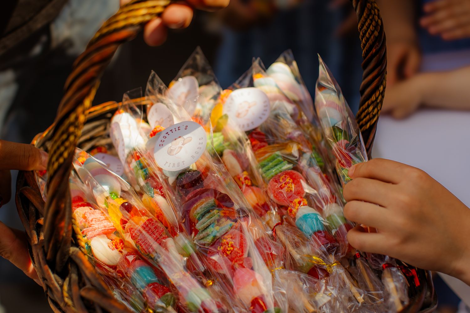 Colorful candy bouquets wrapped in clear cellophane displayed in a wicker basket at a birthday party.